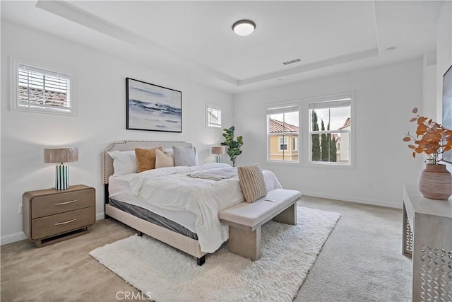 carpeted bedroom featuring baseboards, visible vents, and a raised ceiling