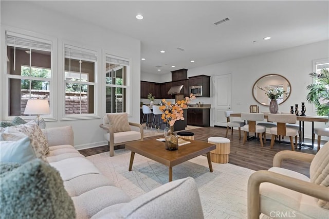 living room with baseboards, light wood-style flooring, visible vents, and recessed lighting