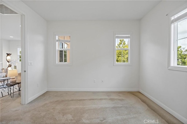 empty room with plenty of natural light, baseboards, and light carpet