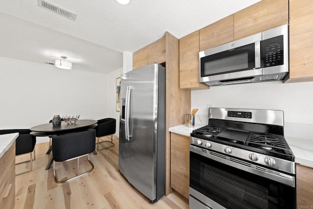 kitchen with visible vents, light wood-type flooring, light countertops, appliances with stainless steel finishes, and a textured ceiling