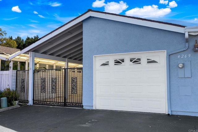 garage with aphalt driveway and fence