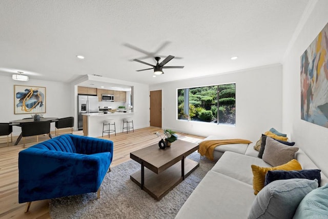 living room featuring baseboards, light wood-style flooring, recessed lighting, ceiling fan, and a textured ceiling