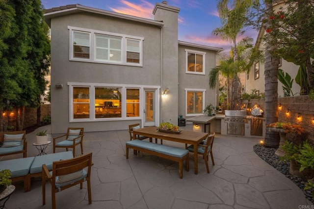 2185 Twain Ave, Carlsbad, CA 92008 - back of property at dusk featuring exterior kitchen, outdoor dining space, stucco siding, and a patio area
