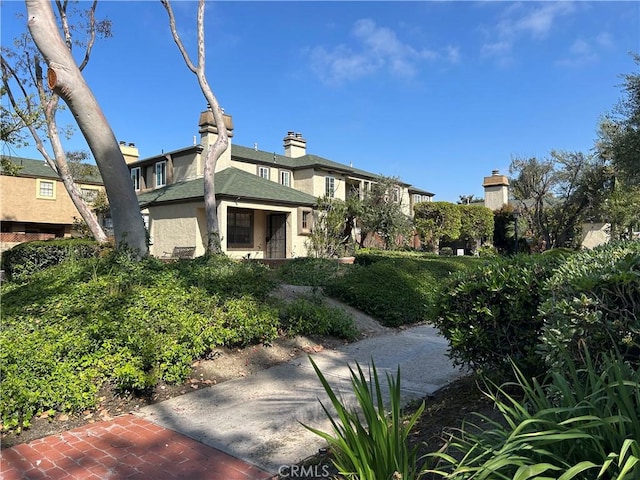 view of front of home with a chimney and stucco siding