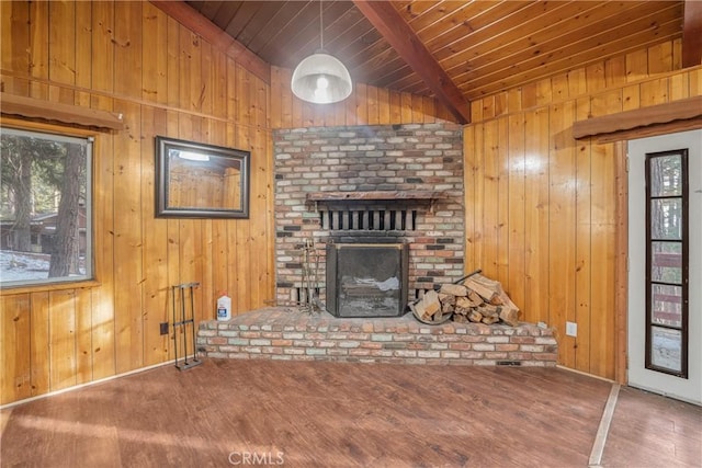 unfurnished living room featuring wood finished floors, wood walls, wooden ceiling, a brick fireplace, and vaulted ceiling with beams