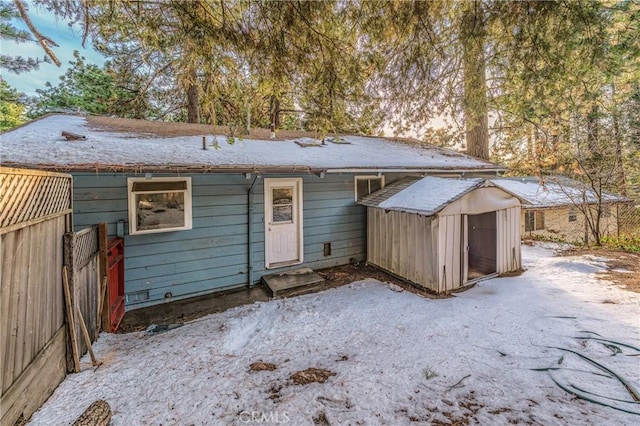 rear view of property featuring an outbuilding, a shed, and fence