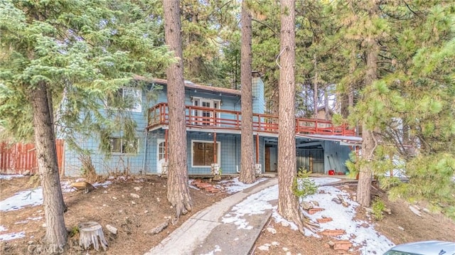 rustic home with a wooden deck, fence, and a chimney