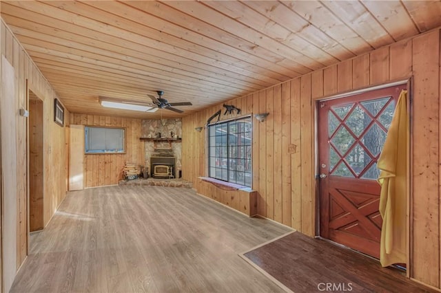 unfurnished living room with wood ceiling, wood finished floors, a ceiling fan, and wood walls