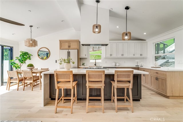 kitchen featuring light wood-type flooring, light countertops, a center island, built in fridge, and vaulted ceiling