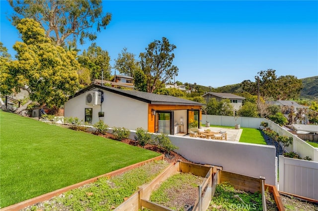 view of front facade featuring a garden, a front yard, fence private yard, a mountain view, and stucco siding