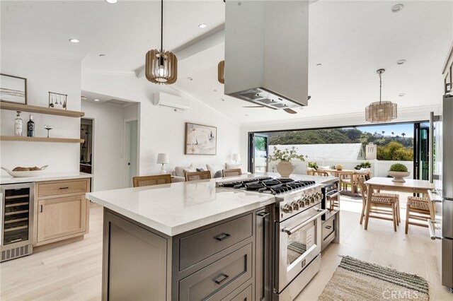 kitchen with an AC wall unit, a center island, high end stove, light wood-type flooring, and wine cooler