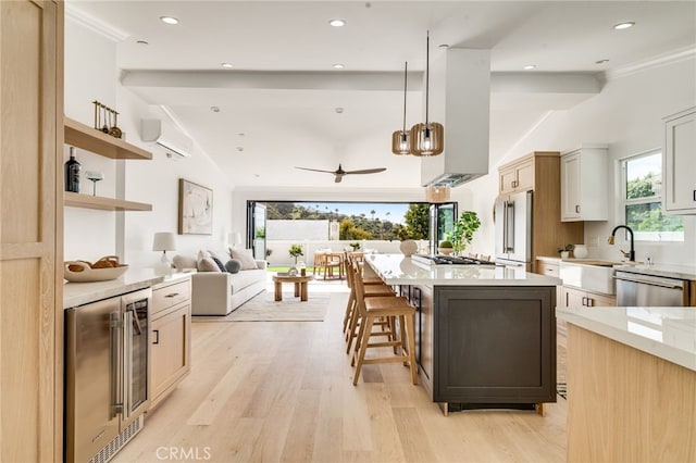 kitchen with vaulted ceiling, an AC wall unit, beverage cooler, stainless steel appliances, and light wood-style flooring