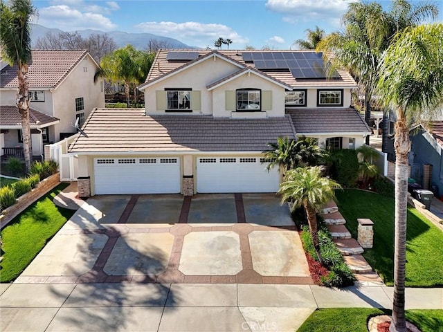 traditional-style home featuring a mountain view, concrete driveway, solar panels, and a tile roof