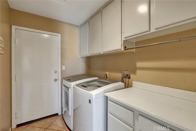 laundry room featuring light tile patterned floors, cabinet space, and washer and clothes dryer