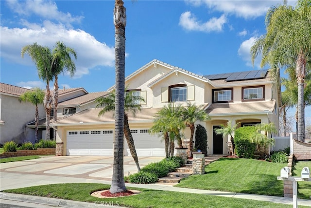 view of front of property featuring a tile roof, stucco siding, a front yard, concrete driveway, and solar panels