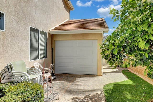 garage featuring fence and concrete driveway