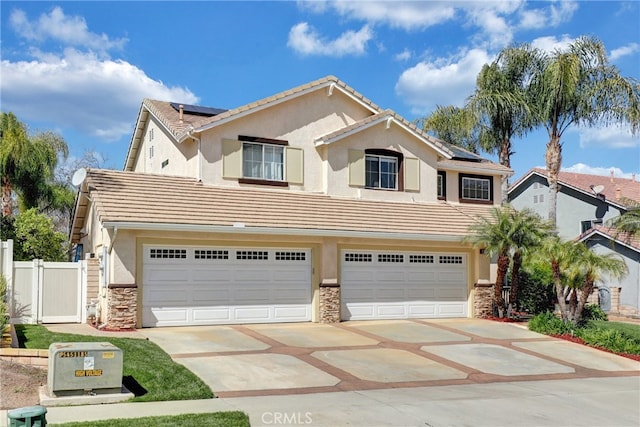 traditional home with stone siding, roof mounted solar panels, concrete driveway, an attached garage, and a tile roof