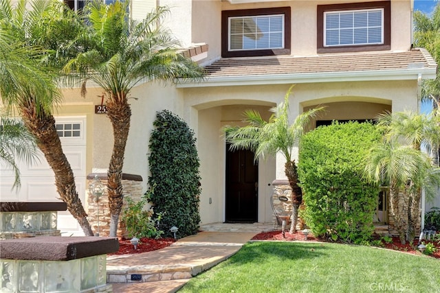 doorway to property featuring a lawn and stucco siding