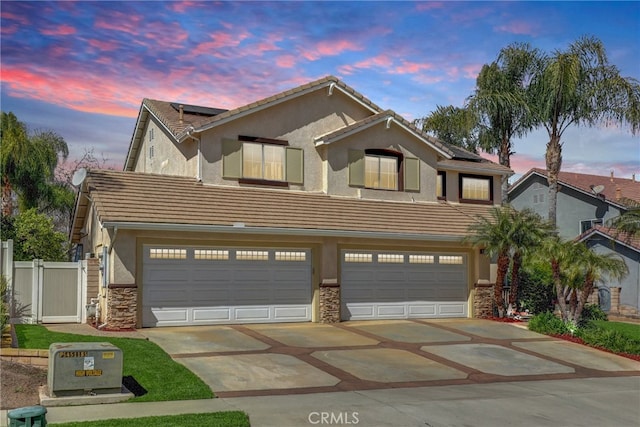 traditional home featuring concrete driveway, roof mounted solar panels, a tile roof, and stucco siding