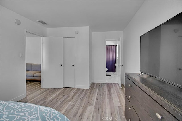 bedroom with a closet, light wood-style flooring, and baseboards
