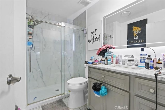 full bathroom with visible vents, a marble finish shower, toilet, and vanity