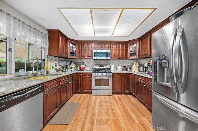 kitchen featuring decorative backsplash, light wood-style flooring, appliances with stainless steel finishes, and a sink
