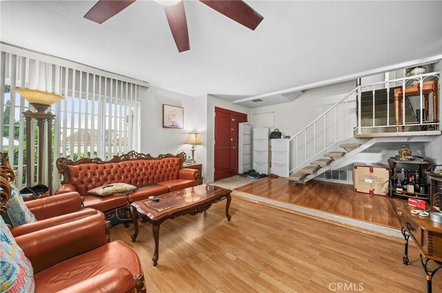 living room featuring stairs, ceiling fan, and wood finished floors