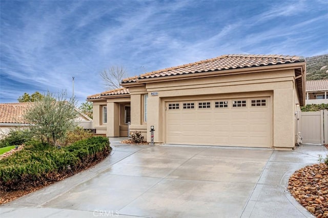 mediterranean / spanish-style house featuring concrete driveway, stucco siding, a tiled roof, and an attached garage