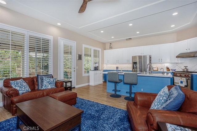 living room featuring light wood-style flooring, recessed lighting, ceiling fan, and baseboards