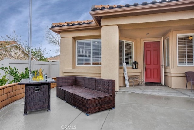 doorway to property with a tiled roof, outdoor lounge area, fence, a patio, and stucco siding