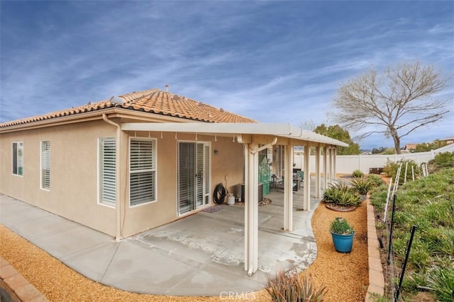 back of property featuring a patio area, stucco siding, a tiled roof, and fence