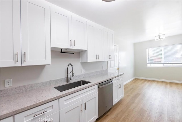 kitchen with stainless steel dishwasher, a sink, light wood-type flooring, baseboards, and white cabinetry
