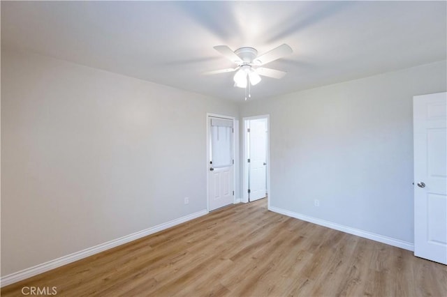 spare room featuring baseboards, a ceiling fan, and light wood-type flooring