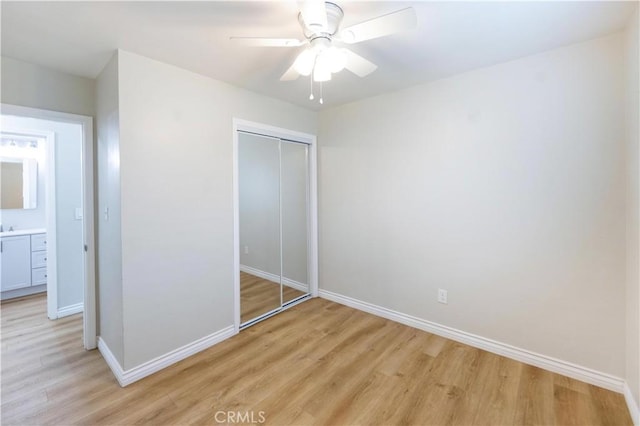 unfurnished bedroom featuring ceiling fan, baseboards, a closet, and light wood-type flooring