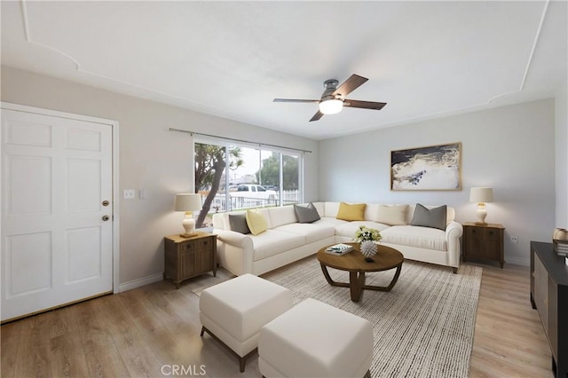 living area featuring light wood-type flooring, a ceiling fan, and baseboards