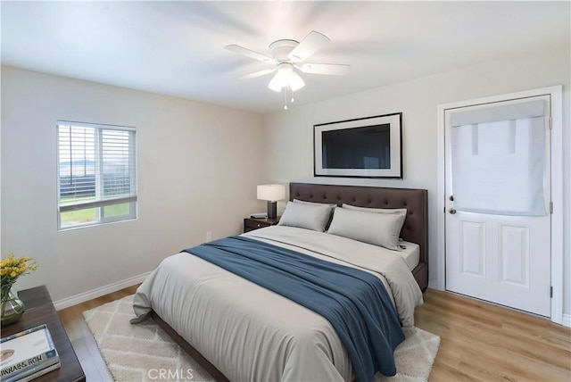 bedroom with light wood-type flooring, a ceiling fan, and baseboards