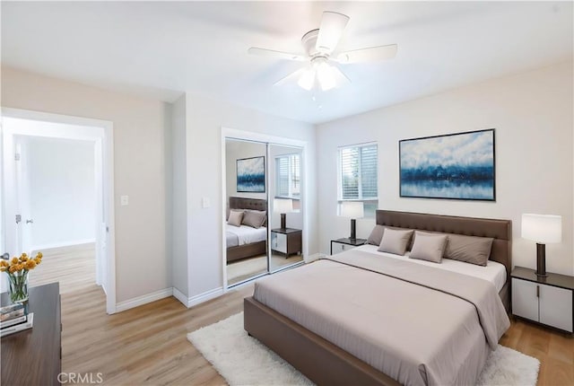 bedroom with light wood-style floors, a closet, a ceiling fan, and baseboards
