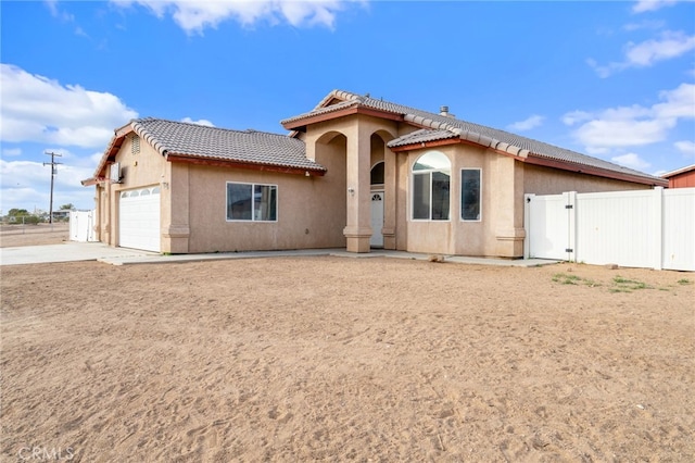 view of front of home featuring fence, stucco siding, a tiled roof, and a gate