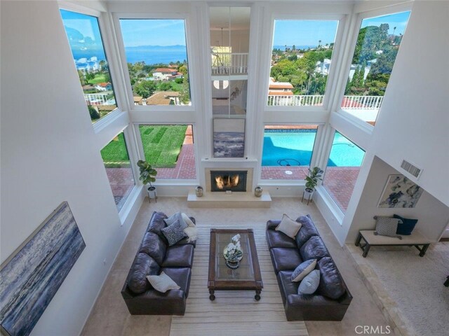 49 Country Ln, Rolling Hills Estates, CA 90274 - unfurnished living room featuring carpet flooring, a towering ceiling, a glass covered fireplace, and visible vents