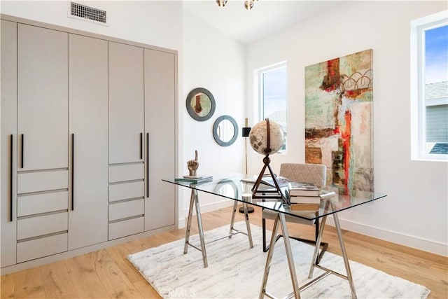 office space with baseboards, visible vents, and light wood finished floors