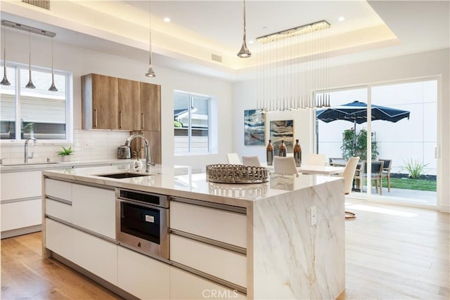 kitchen featuring a sink, decorative backsplash, a raised ceiling, and oven