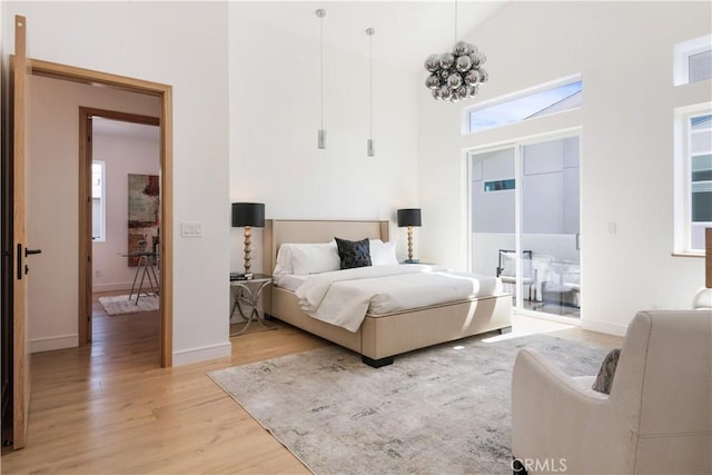 bedroom featuring light wood-type flooring, baseboards, and high vaulted ceiling