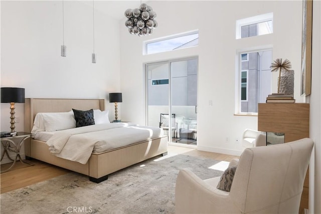 bedroom with a notable chandelier, baseboards, a towering ceiling, and wood finished floors