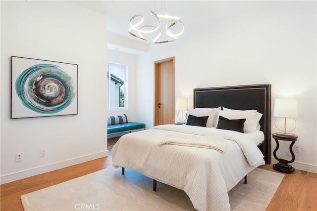 bedroom with baseboards, wood finished floors, and a chandelier