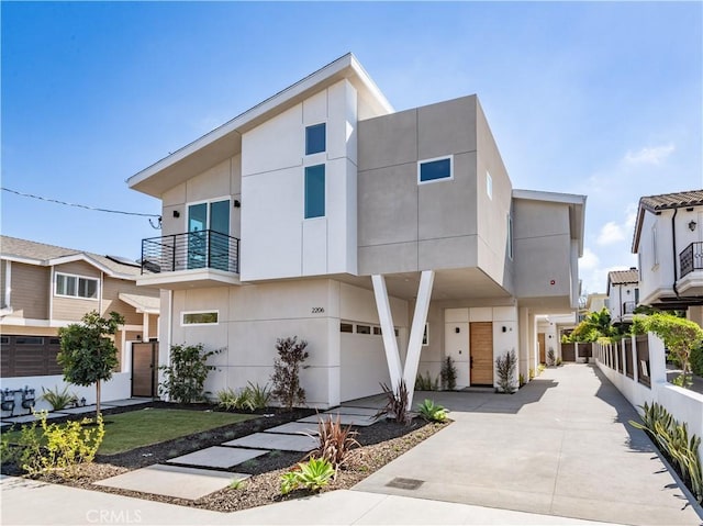 modern home with stucco siding, a garage, and a balcony