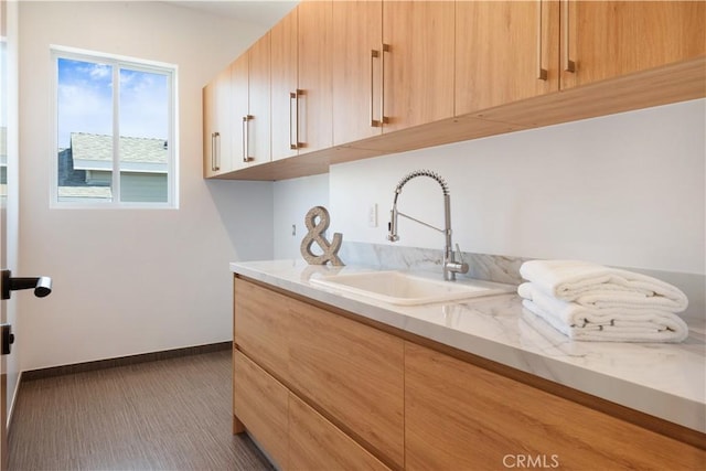 washroom with baseboards and a sink