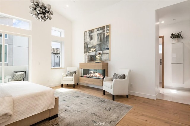 bedroom featuring wood finished floors, baseboards, high vaulted ceiling, recessed lighting, and a multi sided fireplace