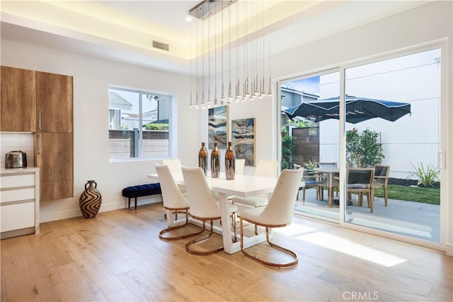 dining room featuring visible vents, baseboards, and light wood-style flooring