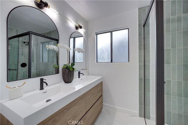 bathroom featuring a sink, marble finish floor, a shower stall, and double vanity
