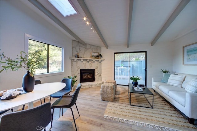 living area featuring lofted ceiling with skylight, a stone fireplace, and wood finished floors